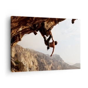 Tablou pe pânză Canvas - Un alpinist pe o stâncă abruptă în munți, la soare - 70x50cm - Lumea s-a micșorat într-un pumn pe un afloriment de bolovani - Decorațiune modernă pentru perete pentru living și dormitor ARTTOR