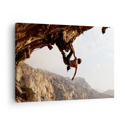 Tablou pe pânză Canvas - Un alpinist pe o stâncă abruptă în munți, la soare - 70x50cm - Lumea s-a micșorat într-un pumn pe un afloriment de bolovani - Decorațiune modernă pentru perete pentru living și dormitor ARTTOR