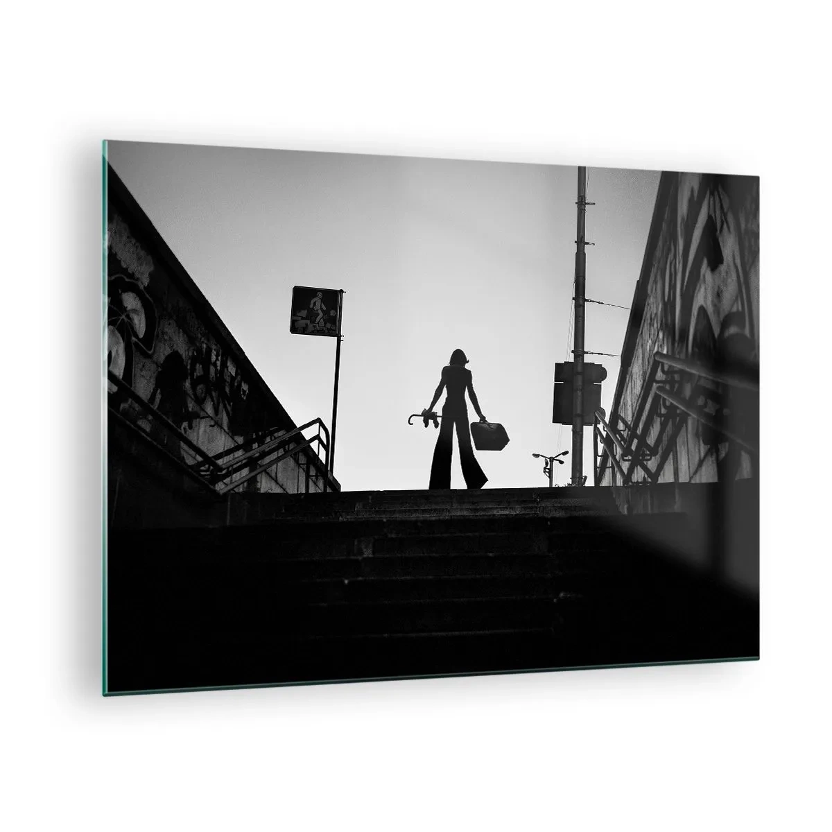 Tablou pe sticlă - Siluetă alb-negru a unei femei pe fundalul unui peisaj urban - 70x50cm - Rătăcire urbană - Decorațiune modernă pentru perete pentru living și dormitor ARTTOR
