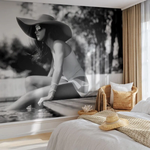 Tapet Standard Eco - O femeie purtând o pălărie stând lângă piscină - 100x70cm - Vis de vară - Decorațiune modernă pentru perete pentru living și dormitor ARTTOR